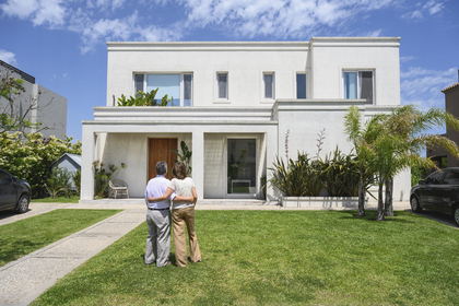 Senior couple admiring family home in front yard