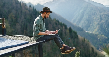 Male freelance author using laptop in mountainscape outdoors