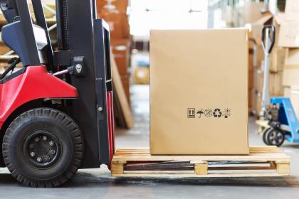 Secure storage facility with packed moving box being lifted by forklift.