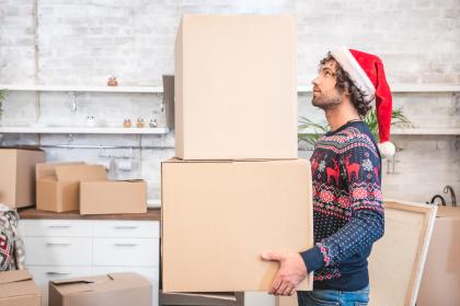 Man wearing Santa hat moving boxes on moving day