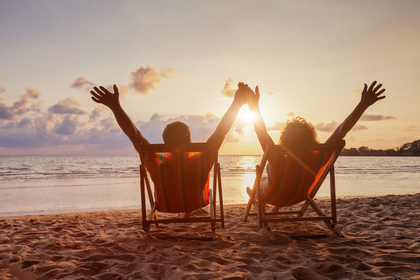 Happy retired couple enjoying sunset near the sea